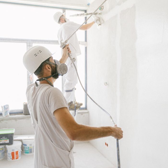 Two professional painters in marbella working indoors on wall renovation and painting project.
